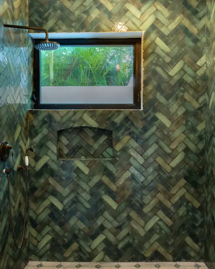Douche entièrement habillée de zellige vert posé en chevrons