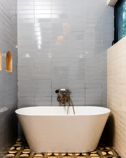 Baignoire îlot devant un mur de faïence bleu-gris