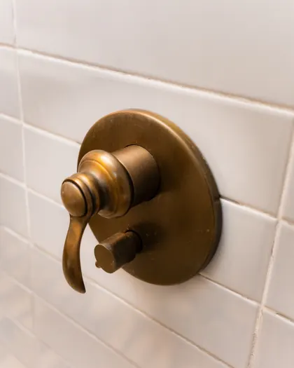 Commande de douche en laiton patiné sur carrelage blanc