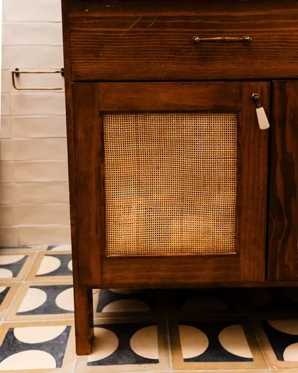 Meuble ancien à portes de cannage sur un sol en demi-lunes