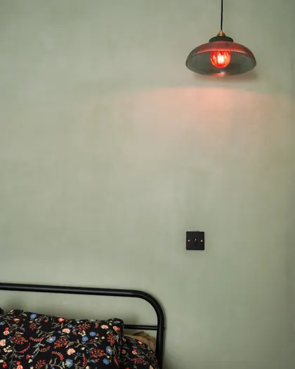 Mur d'enduit vert sauge, suspension de verre nervuré et lit de métal